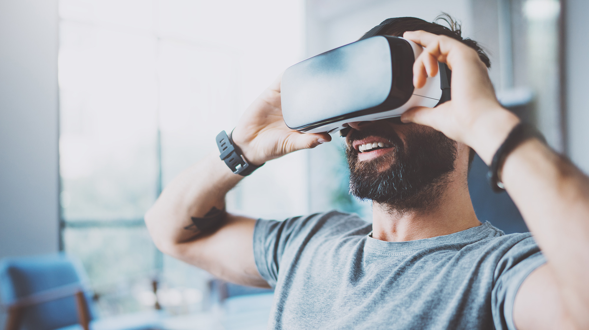 Bearded man wearing virtual reality goggles in modern coworking studio